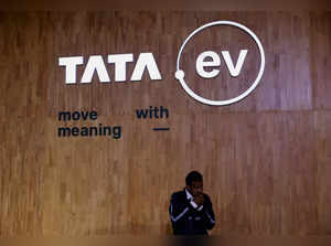 FILE PHOTO: A man stands next to a sign of the brand of  Tata Motors' passenger electric vehicles 'Tata.ev ' at Bharat Mobility Global Expo organised by India's commerce ministry at Pragati Maidan in New Delhi
