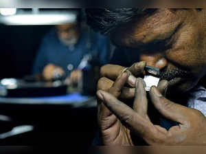 This photograph taken on February 6, 2024 shows Kurjibhai, an employee at Greenlab Diamonds inspecting a lab-grown diamond produced at the manufacturing firm on the outskirts of Surat.