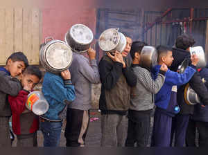 Palestinian children carry pots as they queue to receive food cooked by a charity kitchen, in Rafah in the southern Gaza Strip