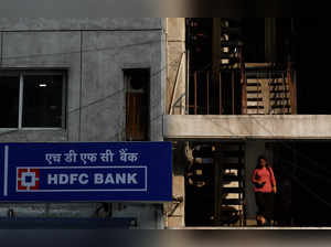 A woman walks past a signboard of HDFC Bank's automated teller machine (ATM) in New Delhi