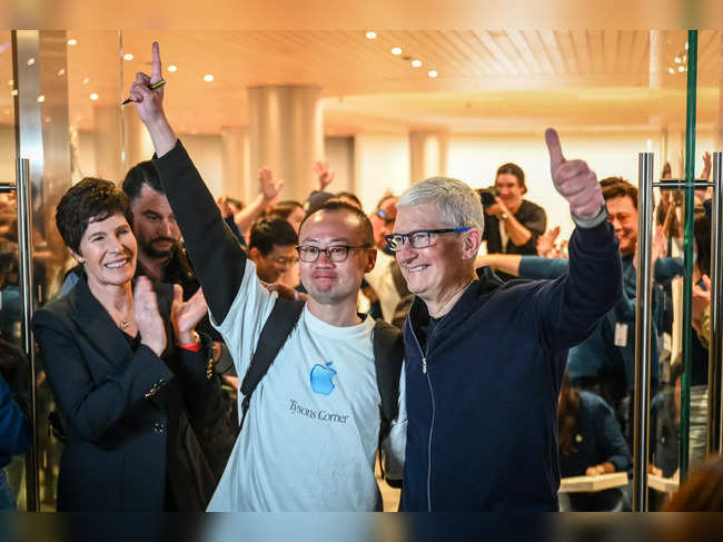 Apple's Chief Executive Officer Tim Cook (R) poses for a picture with a man during the opening of Shanghai's new Apple retail store in Shanghai on March 21, 2024.