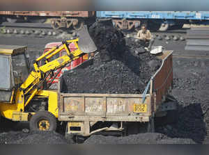 A worker sits on a truck being loaded with coal at a railway coal yard on the outskirts of Ahmedabad