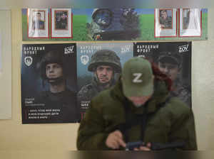 A woman is seen in front of posters and photographs of servicemen at a polling station during Russia's presidential election in Donetsk, Russian-controlled Ukraine, amid the Russia-Ukraine conflict on March 16, 2024.