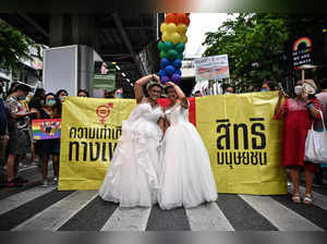 A same-sex couple poses in wedding dresses as members of the LGBTQIA+ community take part in a Pride March in Bangkok on June 5, 2022.