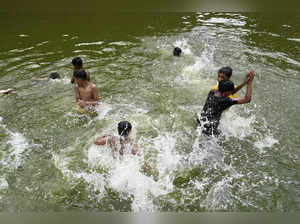Children swim in a pond during a heatwave in Dhaka on April 17, 2024.