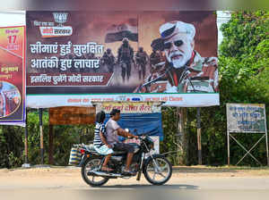 A motorcyclist drives past a poster of India's Prime Minister Narendra Modi in Dantewada district in Chhattisgarh on April 16, 2024, ahead of India's national elections.