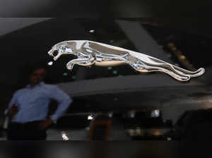 FILE PHOTO: A man is reflected in the logo of a Jaguar vehicle at a Jaguar Land Rover showroom in Mumbai