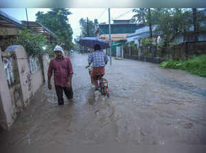 Kochi: Commuters on a flooded road during rain, in Kochi. The Indian Meteorologi...