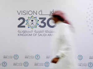 FILE PHOTO: A Saudi man walks past the logo of Vision 2030 after a news conference in Jeddah