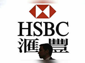 This picture taken on May 2, 2019 shows a man walking past a backlit display of the HSBC logo in Hong Kong.