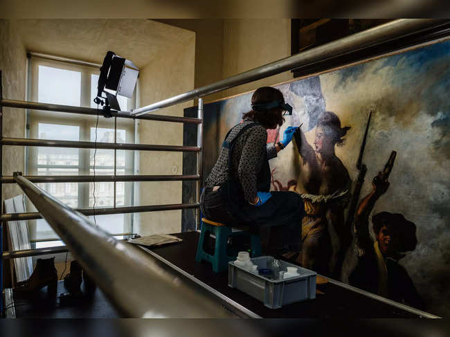 A restoration artist works on the restoration of the painting "Liberty Leading the People" (1830) by French artist Eugene Delacroix (1798-1863), at a laboratory inside the Louvre Museum in Paris, on February 28, 2024.