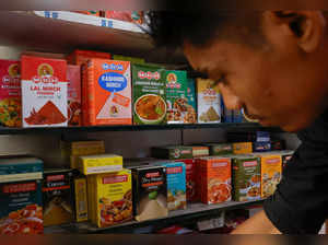 A man stands near the spice boxes of MDH and Everest kept on the shelf of a shop at a market in New Delhi