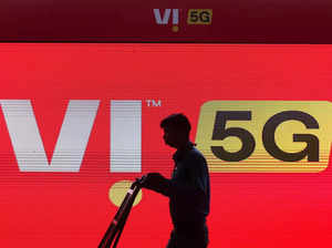 FILE PHOTO_ A man walks across the LED display board showing the logo of Vodafone-Idea at the ongoing India Mobile Congress 2022, at Pragati Maidan, in New Delhi.