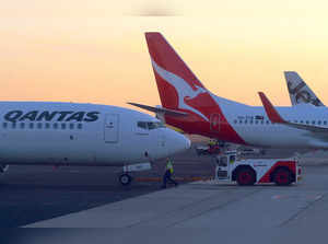 FILE PHOTO: Workers are seen near Qantas Airways, Australia's national carrier, Boeing 737-800 aircraft on the tarmac at Adelaide Airport