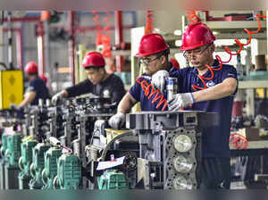 Employees work on an engine assembly line at an engine manufacturing factory in Qingzhou, in China's eastern Shandong province on April 16, 2024.