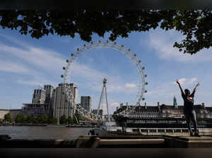 A woman enjoys the weather as the London Eye is seen in the background in London