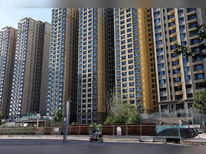 FILE PHOTO: A woman rides a scooter past residential buildings at an Evergrande residential complex in Beijing
