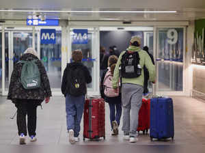People walk carrying their luggage at Linate Airport in Milan