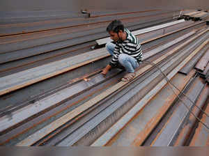 FILE PHOTO: A worker cuts iron rods outside a workshop at an iron and steel market in an industrial area in New Delhi