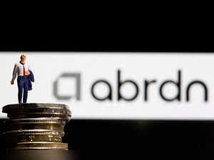 FILE PHOTO: Businessman toy figure is placed on U.K. Pound coins in front of displayed Abrdn logo in this illustration taken