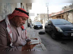 A man reads the Koran as he sits on a pavement in the Palestinian refugee camp of Baqa'a near Amman on May 22, 2024.