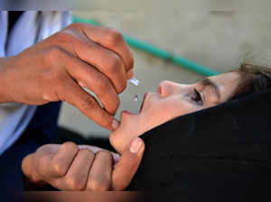 An Afghan health worker (L) administers polio vaccine drops to a girl child during a polio vaccination campaign in Kandahar on April 29, 2024.