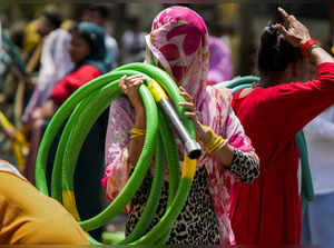 New Delhi: A woman carries a water pipe amid the ongoing water crisis, at Chanak...
