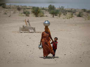 A woman walks back towards her home after filling water from a shallow well in the desert area in Barmer