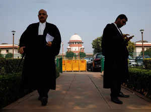 FILE PHOTO: A lawyer looks into his mobile phone as another walks past, in front of India's Supreme Court in New Delhi
