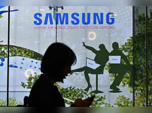 A woman walks past the Samsung logo displayed on a glass window at the company's Seocho building in Seoul on April 30, 2024.