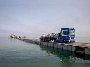 FILE PHOTO: Trucks deliver humanitarian aid over a temporary pier on the Gaza coast