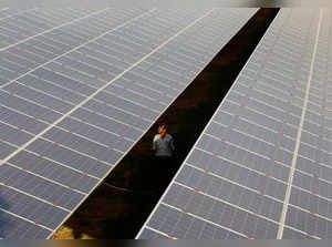 FILE PHOTO: A private security guard walks between rows of photovoltaic solar panels inside a solar power plant at Raisan
