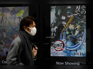 A man wearing a protective mask amid the coronavirus disease (COVID-19) outbreak walks past a poster for an animated movie "Demon slayer" in front of a movie theatre in Tokyo