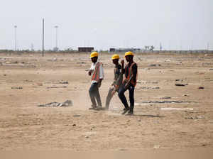 Labourers walk past near construction site of Tata Group semi-conductor fabrication plant at Dholera