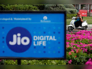 A woman rides her scooter past advertisements of Reliance Industries' Jio telecoms unit, in Ahmedabad