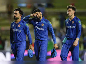 Afghanistan's captain Rashid Khan, left, walks with his teammates from the field...