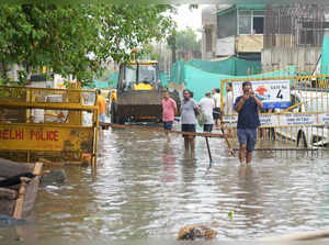 New Delhi: Residents on a waterlogged road after heavy rains, in New Delhi, Frid...