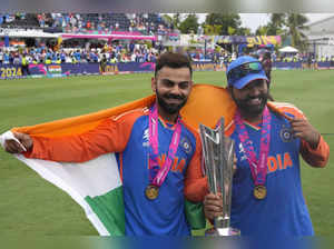 India's Virat Kohli, left, and captain Rohit Sharma pose with the winners trophy...