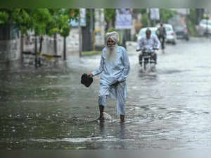 An elderly man wades through a waterlogged street after heavy rainfall in Amritsar on June 30, 2024.