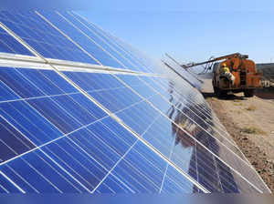 FILE PHOTO: Worker operates a machinery to clean solar panels at a photovoltaic industrial park in Hami