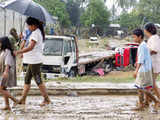 Residents walk past trucks swept away by flash floods