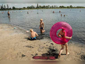 People sunbath on a lake beach during a summer heat wave in Sloviansk