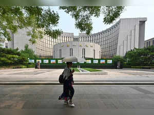 A woman walks past the headquarters of the People’s Bank of China, the country’s central bank, in Beijing on July 9, 2024.