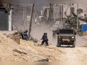 Reporters work as Israeli army vehicles drive during a raid in the Nur Shams camp for Palestinian refugees in the occupied West Bank on July 9, 2024.