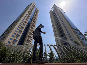 A worker waters the plants during morning hours in a residential area, in Manama