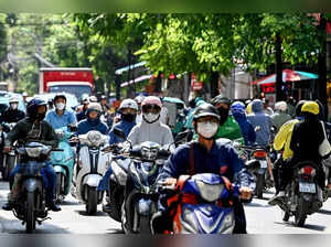 People ride motorbikes on a street in Hanoi on July 8, 2024.