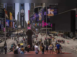 People walk by blacked out screens due to a global technology outage  in Times S...