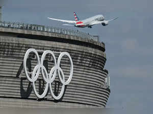 This photograph taken in Roissy-en-France on April 23, 2024, shows an aircraft taking off past the Olympic rings displayed on the Roissy - Charles de Gaulle Airport Terminal 1, north of Paris, ahead of The Paris 2024 Olympics which are scheduled to take place from July 26 to August 11, 2024.