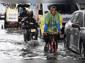 A cyclist rides through through a flooded street in Manila on July 23, 2024, amid heavy rains brought about by Typhoon Gaemi.