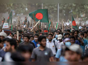 Anti-quota protesters march with Bangladeshi flags and sticks as they engage in a clash with Bangladesh Chhatra League, the student wing of the ruling party Bangladesh Awami League, at the University of Dhaka